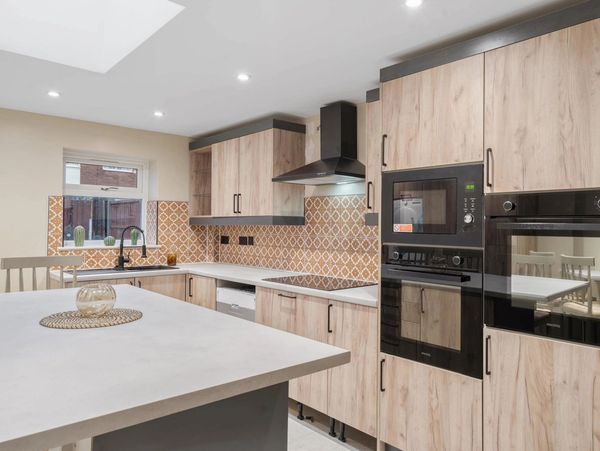 Modern kitchen with wood cabinets and terracotta patterned tile backsplash.