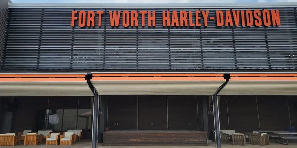 Exterior view of Fort Worth Harley-Davidson dealership with seating area.