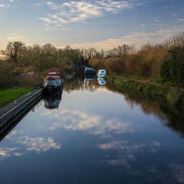 Boats moored on a calm canal at sunset.