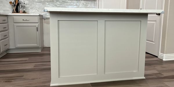 Modern kitchen island with white cabinets and wood flooring.
