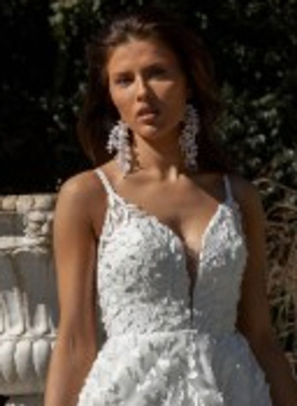 Woman in a white lace dress with large earrings outdoors.