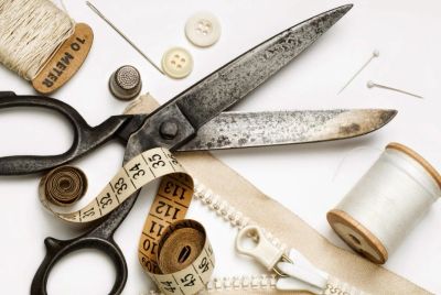 Vintage sewing tools including scissors, measuring tape, thread, and zipper.