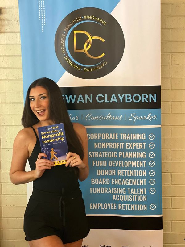 Woman holding a book in front of a professional banner for nonprofit leadership.