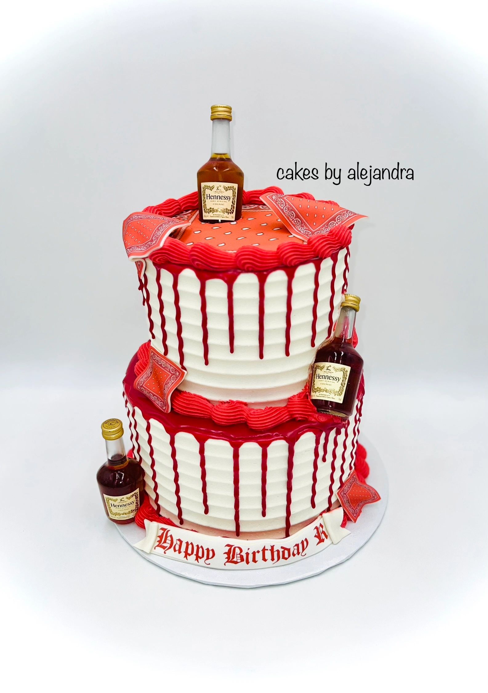 Two-tier white and red drip cake decorated with mini Hennessy bottles and bandana patterns.