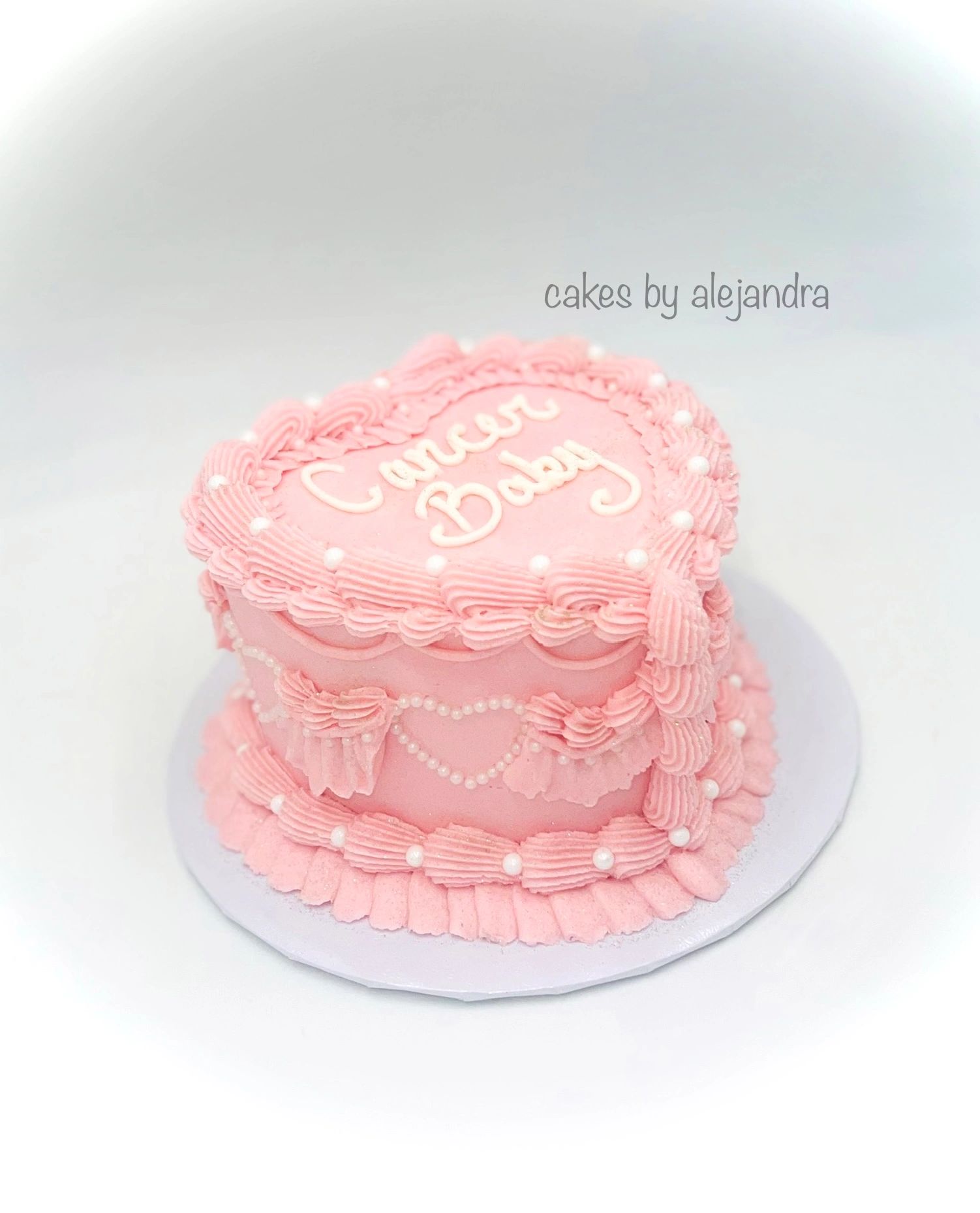 Pink heart-shaped cake with "Cancer Baby" written on top.