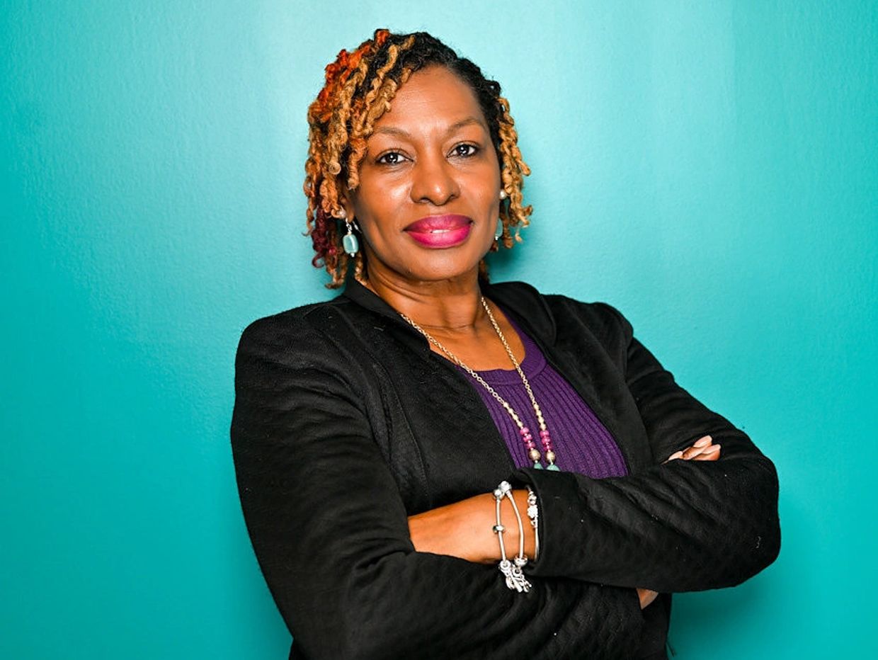 Confident woman with crossed arms and colorful hair.