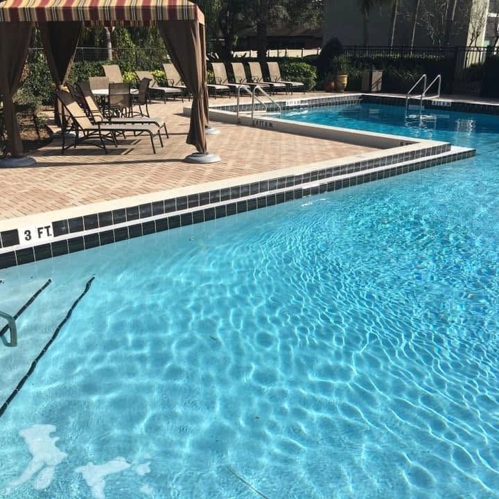 Sunny poolside with loungers and clear water.