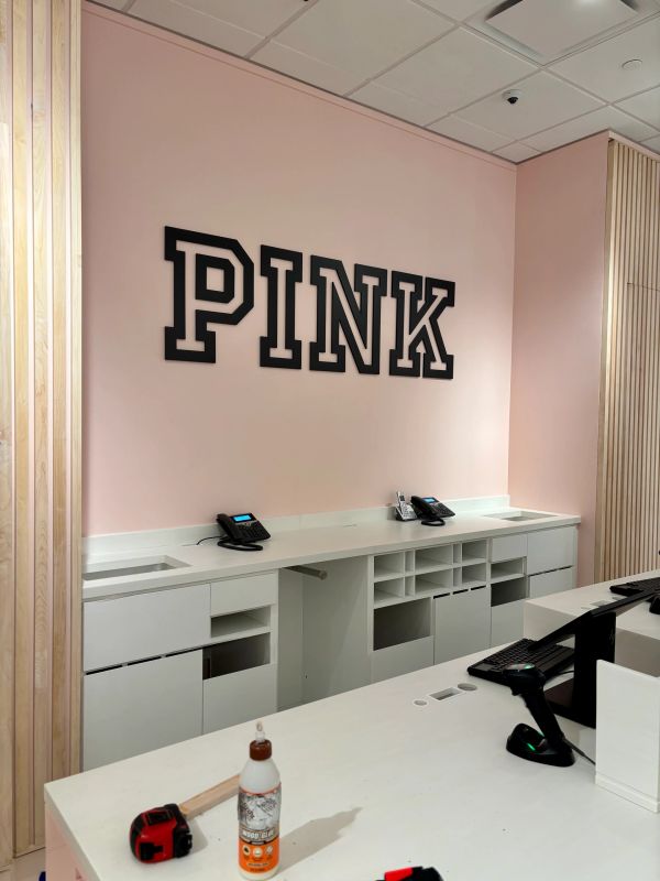 Modern office space with pink walls and black PINK lettering.