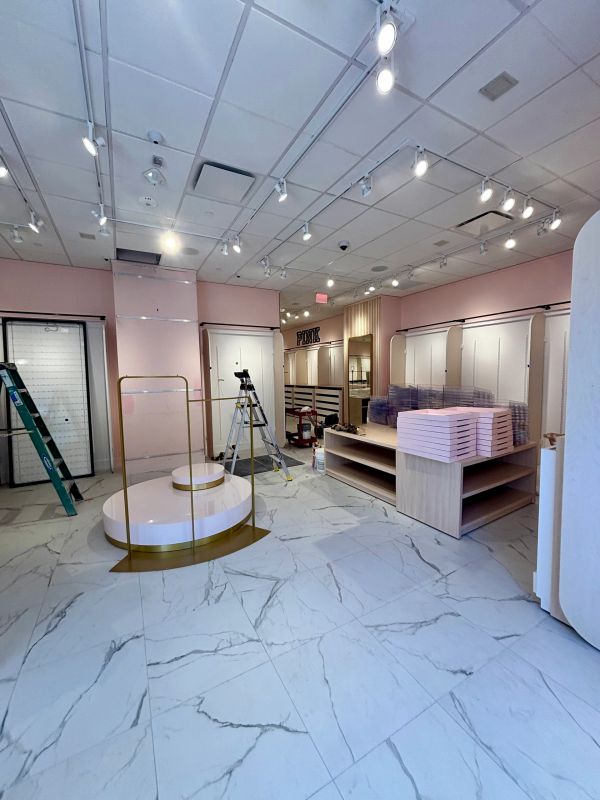 Interior of a modern retail store under setup with pink walls and marble floors.