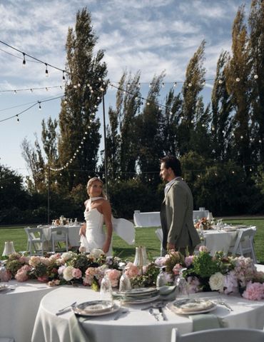 Bride and groom at an outdoor wedding reception with floral decorations.