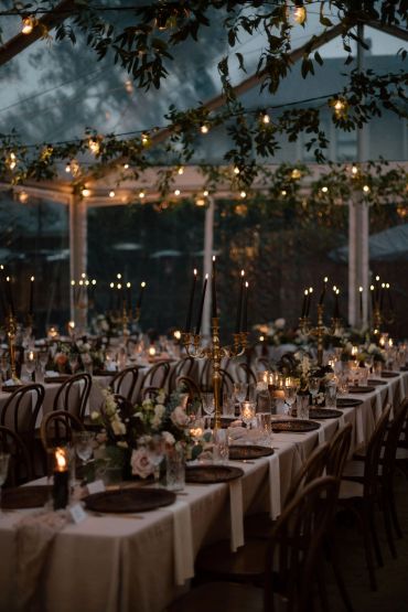 Elegant outdoor dining setup with string lights and floral centerpieces.