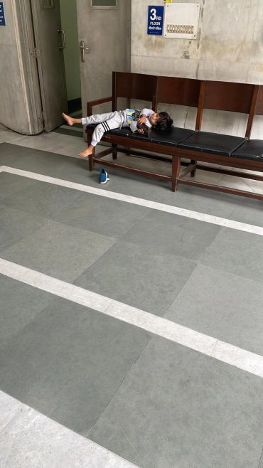 Child resting on a bench in a corridor.