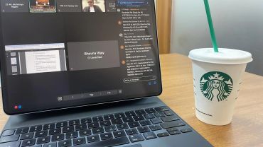Laptop displaying an online meeting beside a Starbucks cup.