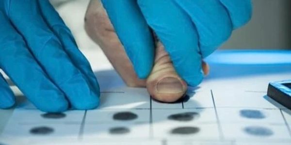 Lab tech fingerprinting a person’s thumb