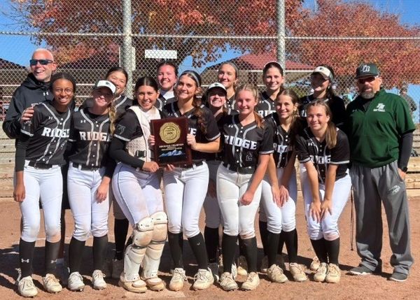 Girls' softball team posing with a championship plaque.
