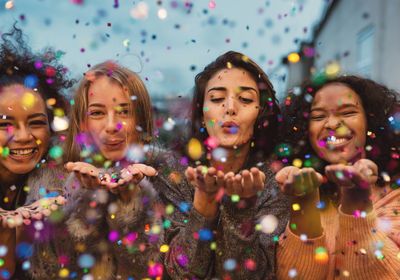 Four women blowing confetti.  Seeking women's therapy.