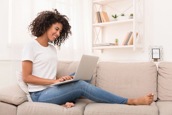 Woman sitting on couch on computer.  Seeking virtual therapy.