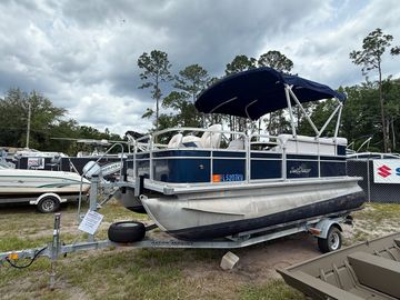 Pontoon boat on a trailer under cloudy sky.