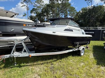 White and black boat on trailer at grassy lot.