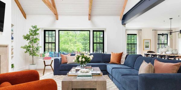 Bright living room with blue sectional sofa and orange armchairs.