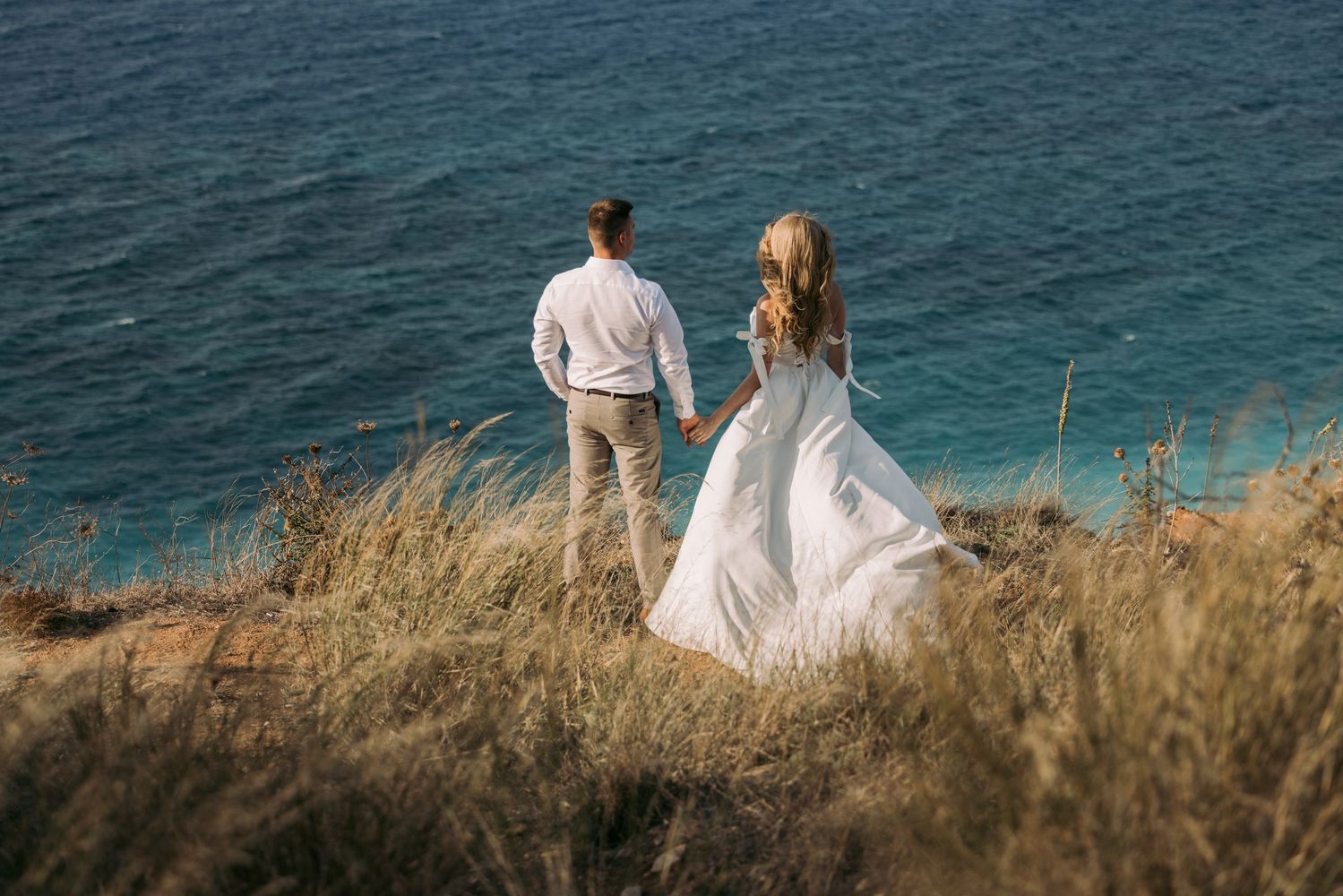 Bride and groom holding hands overlooking the Aegean Sea in Rhodes for a destination wedding.