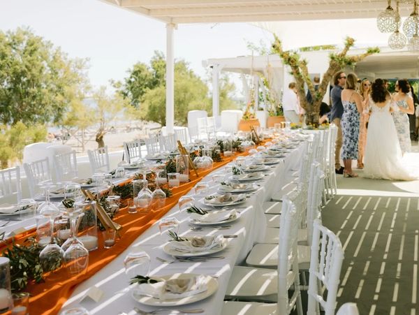 Outdoor Rhodes wedding reception with elegant long tables and white décor near the beach.