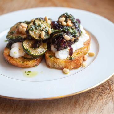 Toasted bread topped with grilled zucchini, cheese, and pine nuts.