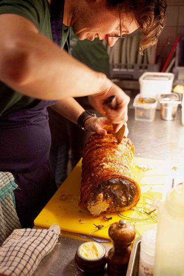 Chef preparing a roasted pork dish.
