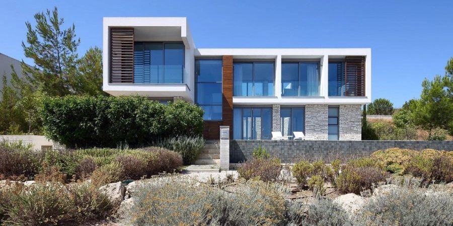Modern house with large glass windows and natural landscaping.