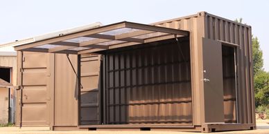 A brown shipping container converted into a small, open structure.