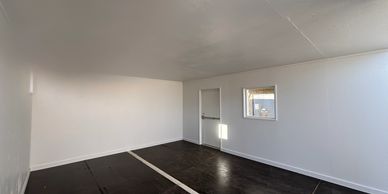 Empty room with white walls and dark floor.