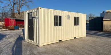 A beige portable storage container with barred windows.