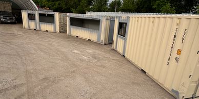 Several tan shipping containers repurposed as small shelter units.