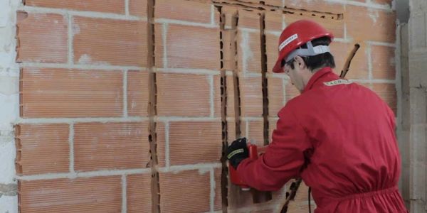 Trabajador realizando trabajos de regolas en una pared de ladrillos.