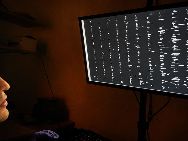 Person analyzing data on a computer screen in a dimly lit room.