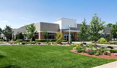 Modern commercial building with landscaped garden and clear blue sky.