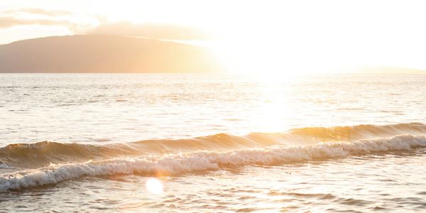 Waves during sunset with island in the background