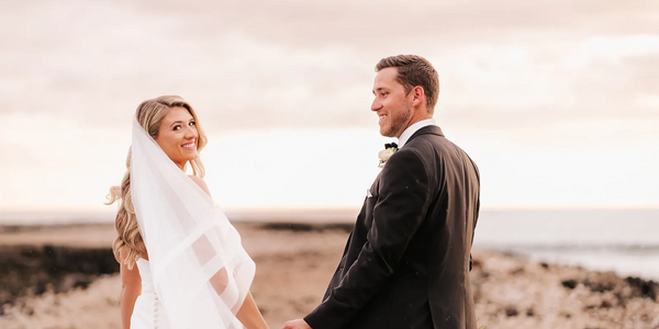 Bride and groom holding hands as bride looks back toward the camera