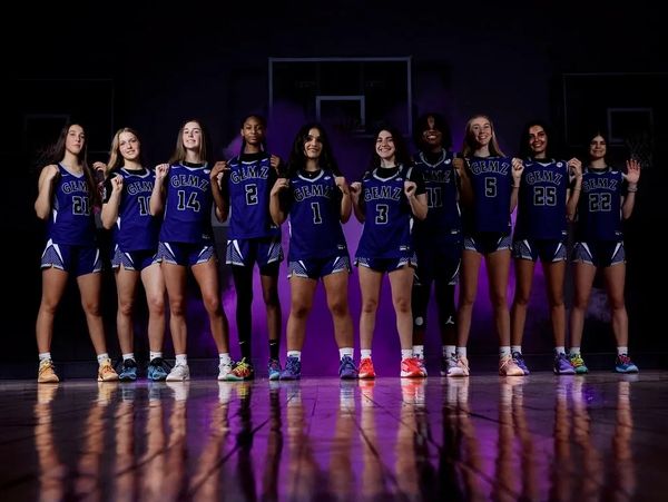 Girls basketball team posing confidently in uniform.