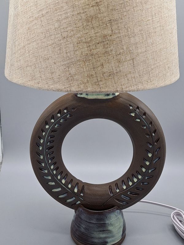 A large Donut Lamp with Green Vines carved into a dark brown clay.