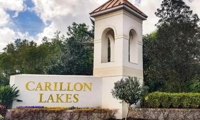 Entrance sign for Carillon Lakes community with a tower and greenery.