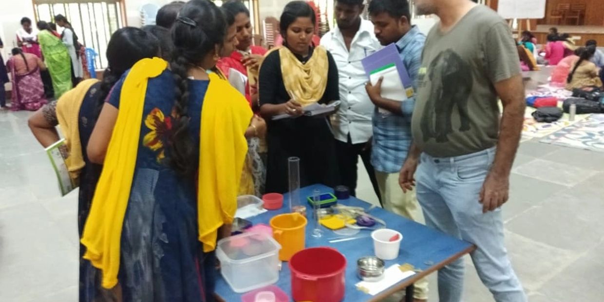 Group of people gathered around a table with containers and scientific tools.