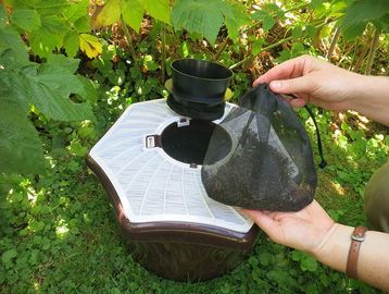 Person removing mesh bag from outdoor insect trap.