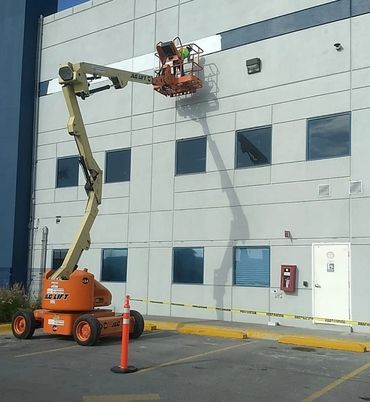 A cherry picker lift being used to work on a building facade.