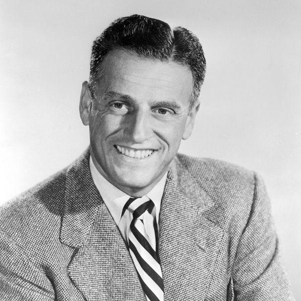 Smiling man in a suit and striped tie, black and white portrait.