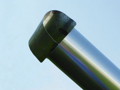 Close-up of a metallic cylindrical object with a curved tip against a clear sky.