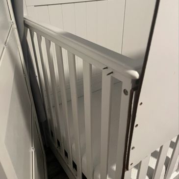 Close-up of a white baby crib with slatted sides.