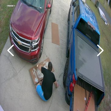 Person assembling an item on the driveway between two trucks.