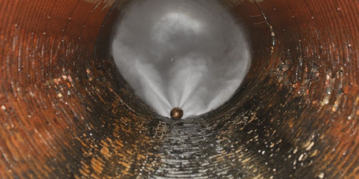 Cleaning a rusty pipe with a spraying device inside.