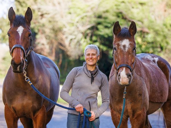Photo of Lynn Mead holding a brown horse in each hand